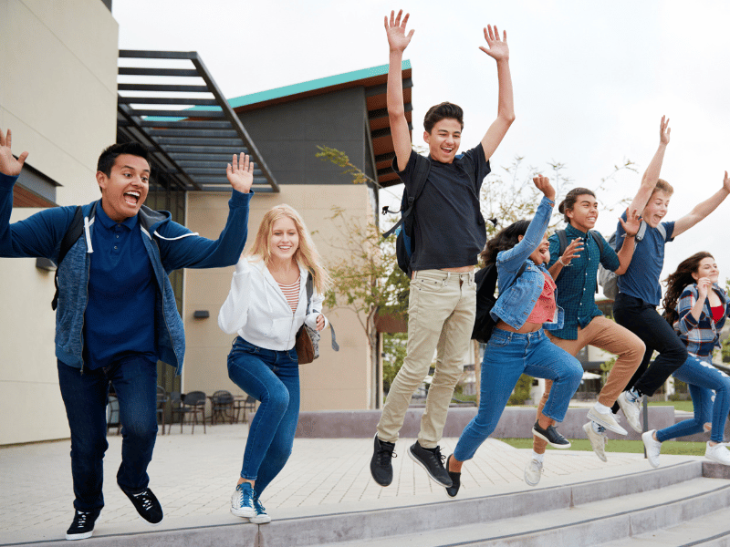 A group of happy students jumping at school. Join our UK School Immersion programme at Oxford International!